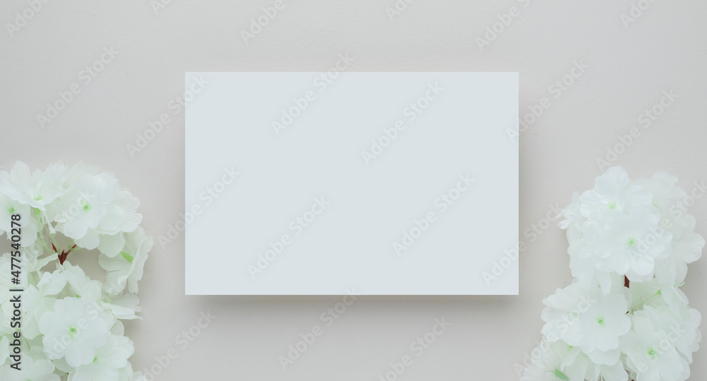 White invitation card mockup with a white flower on beige background, Minimal beige workplace composition, flat lay, mockup White invitation card mockup with a white flower on beige background, Minimal beige workplace composition, flat lay, mockup