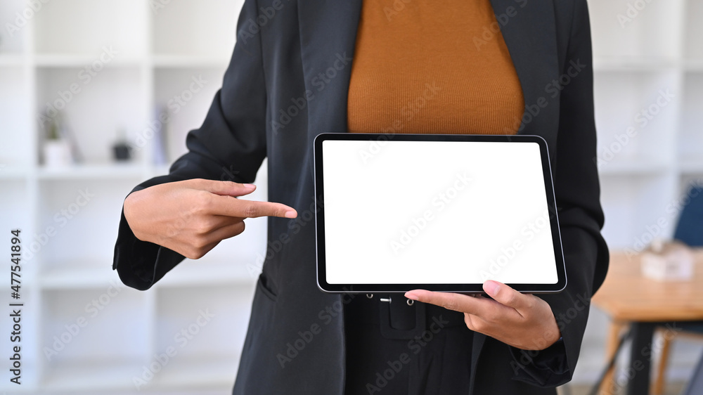 Cropped image of businesswoman holding and showing digital table with white screen. Cropped image of businesswoman holding and showing digital table with white screen.