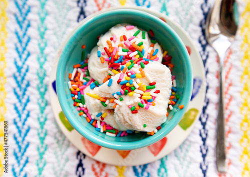 Fotografía vanilla ice cream with rainbow sprinkles in turquoise bowl on colorful placemat