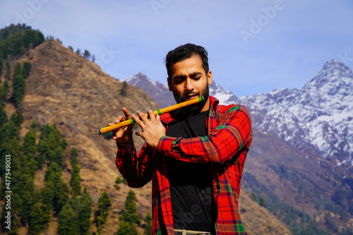 Young boy playing bansuri Indian flute in mountains photo