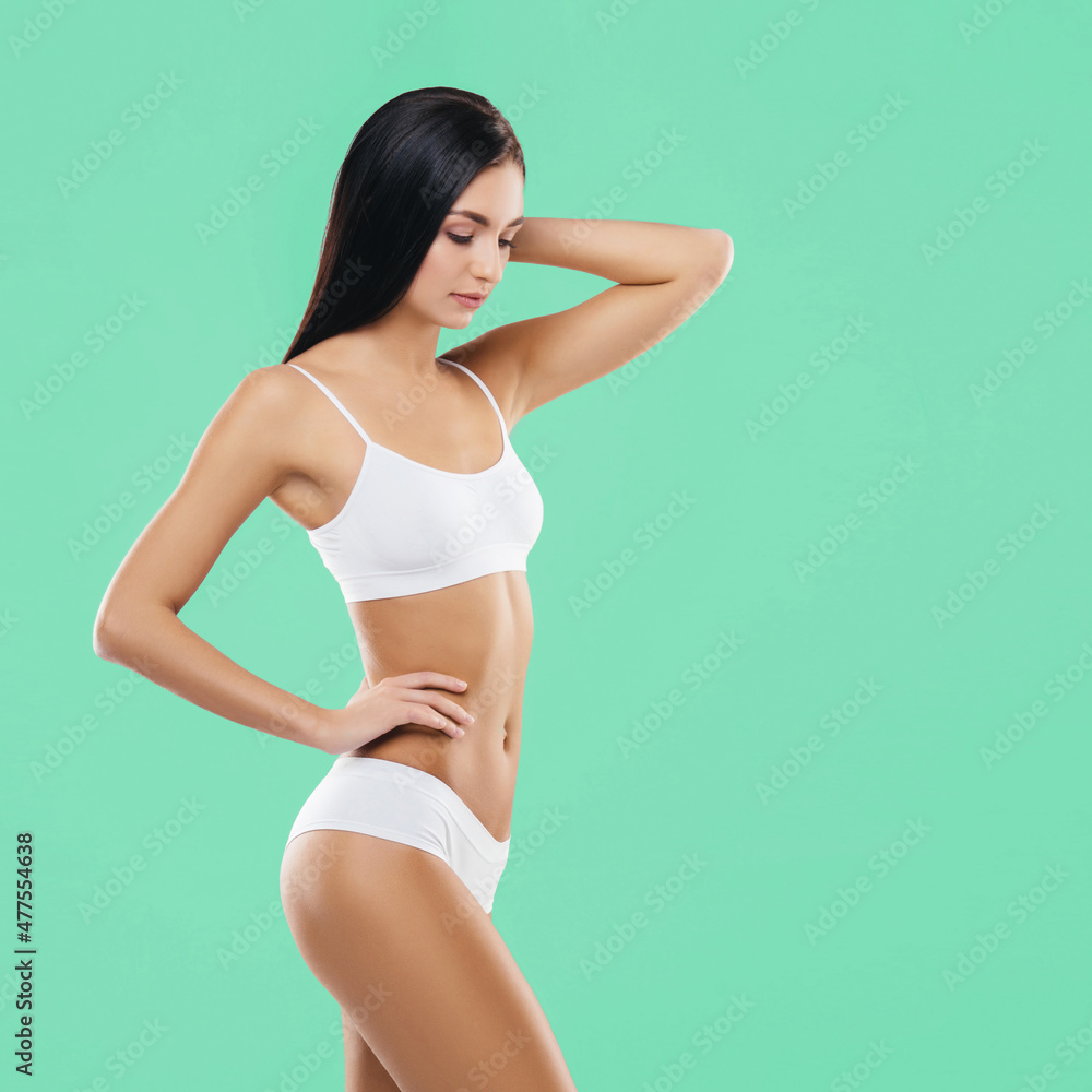Young, fit and beautiful brunette woman in white swimsuit posing in studio. Concept of fitness, dieting and skin care. Young, fit and beautiful brunette woman in white swimsuit posing in studio. Concept of fitness, dieting and skin care.