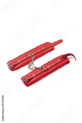 Detailed shot of unbuckled red handcuffs with steel rivets, buckles and faux fur inside. The wristbands are connected by a steel chain and isolated on the white background. photo