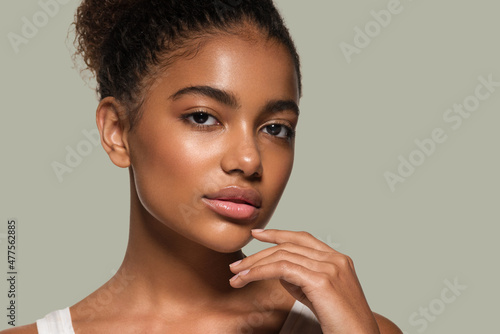Beauty woman black skin face smiling model touching her face. Color background. Green