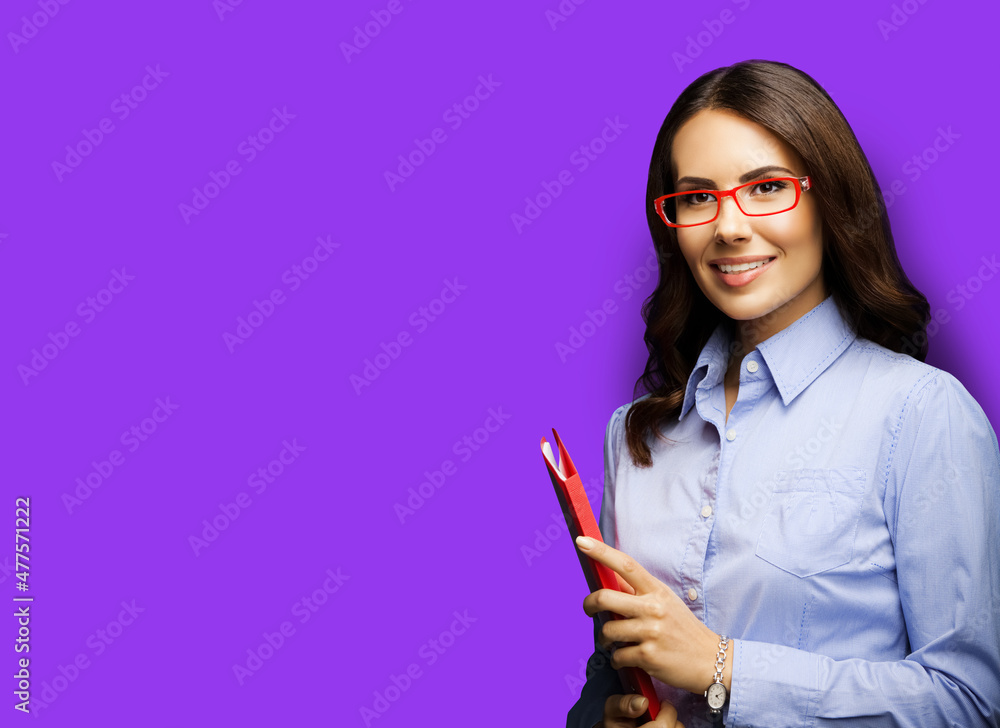 Portrait of smiling businesswoman in eye glasses spectacles holding red folder. Image of young brunette business woman at studio, isolated over violet color background.