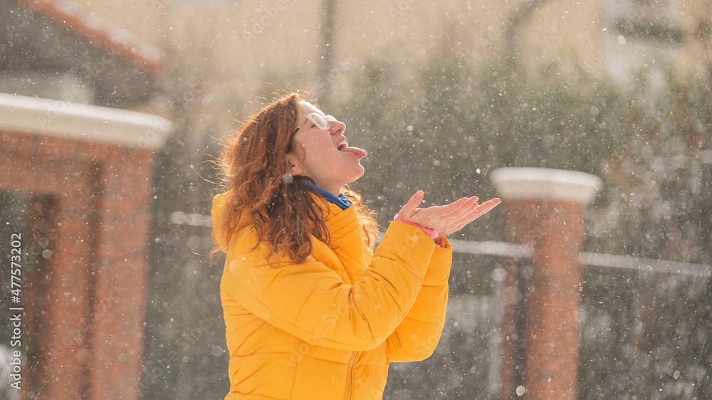 Obraz premium Red-haired Caucasian woman rejoices in winter and catches snowflakes with tongue.