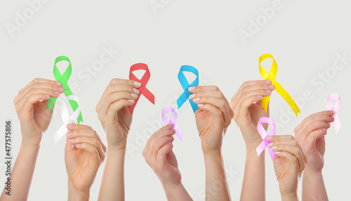 Many hands holding different ribbons on grey background. World Cancer Day