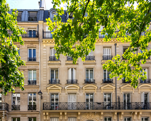 Photography Traditional bulding with typical windows and balconies in bright summer day as seen through tree leaves