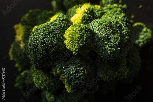 Frozen green broccoli florets on dark background closup