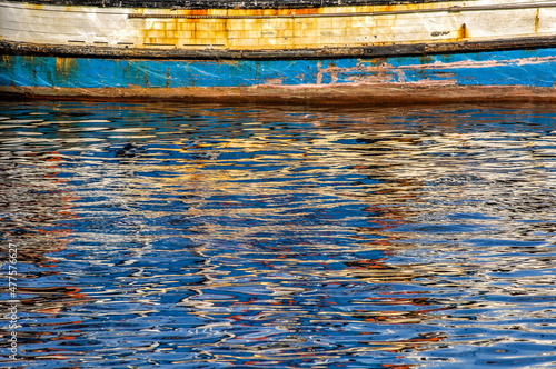 An abstract horizontal colourful close up of ripples on the surface of the sea, Cape Town, South Africa with interesting reflections from a boat creating patterns in the water