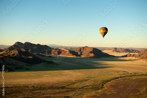 A horizontal shot of a hot air balloon flight over the Sossusvlei National Park landscape at sunrise, Namibia