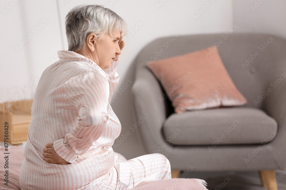 Senior woman suffering from back pain on bed at home Senior woman suffering from back pain on bed at home