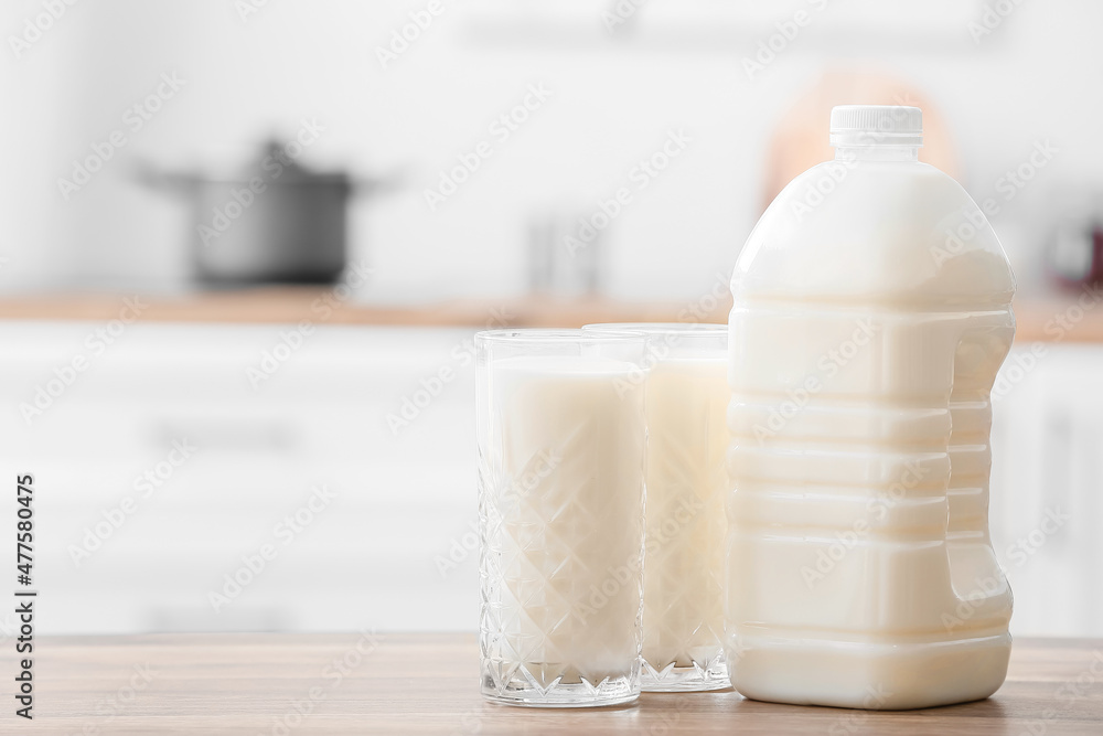Gallon bottle and glasses of milk on table in kitchen Gallon bottle and glasses of milk on table in kitchen