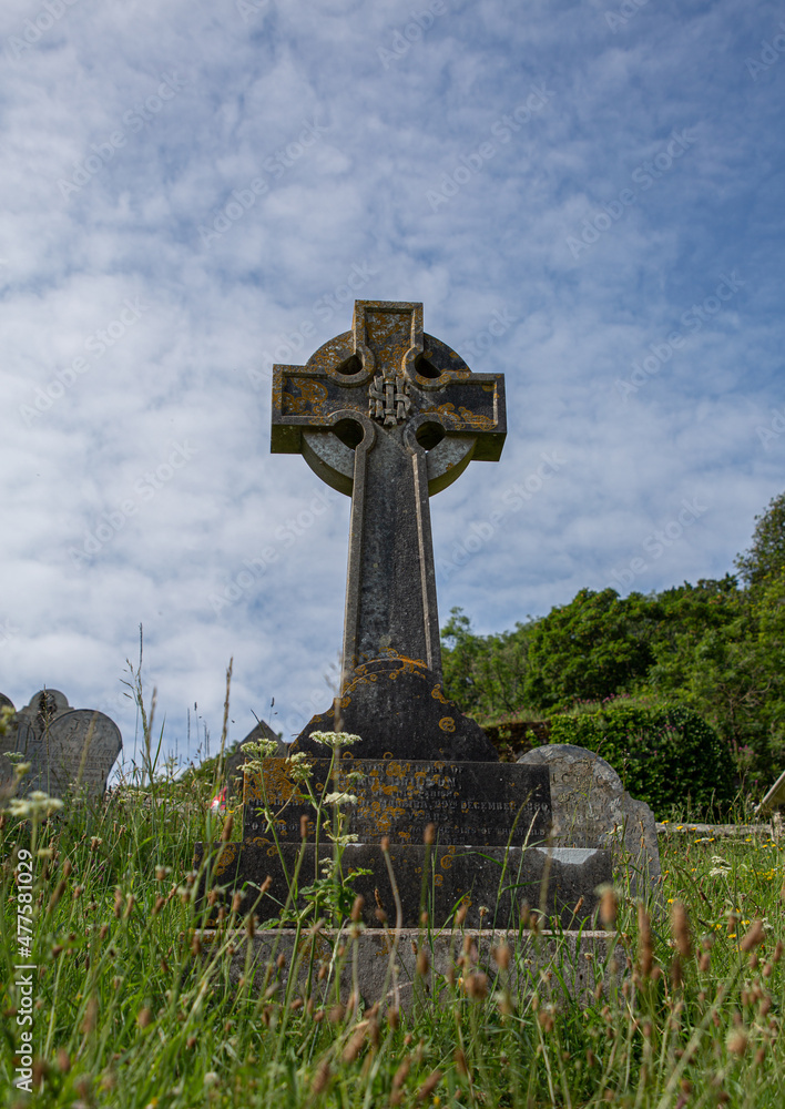 Celtic cross gravestone in the grass with blue background and some clouds