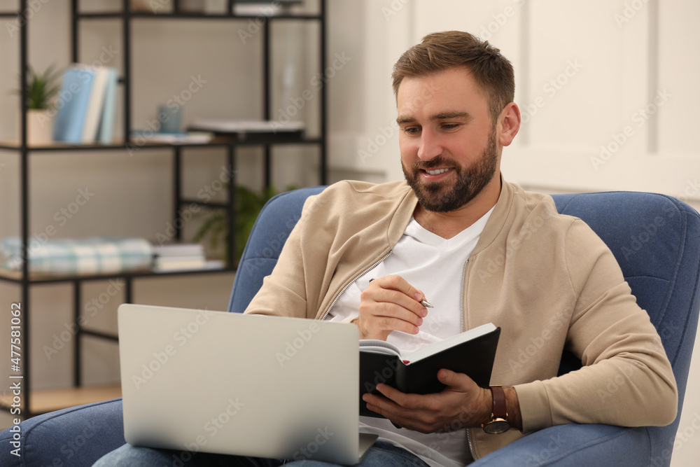 Young man working with notebook and laptop at home Young man working with notebook and laptop at home