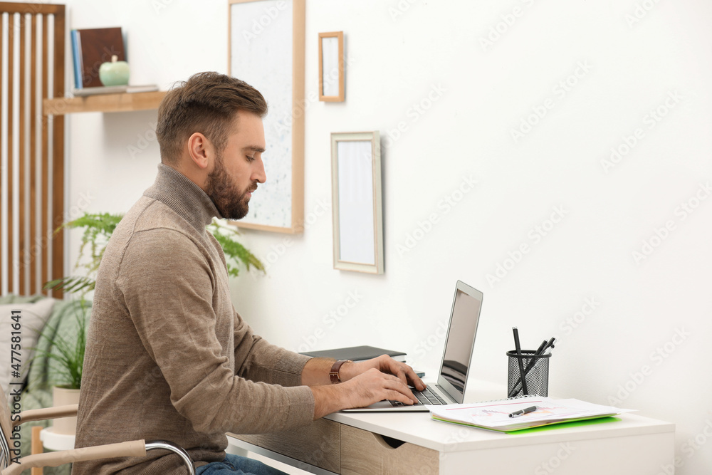 Young man working with laptop at home, space for text Young man working with laptop at home, space for text