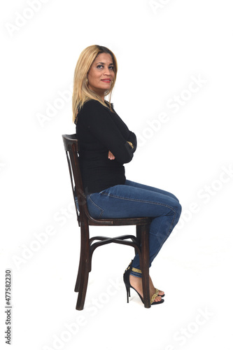 Side view of portrait of a woman with jeans and heeled shoes looking at camera and arms crossed on white background