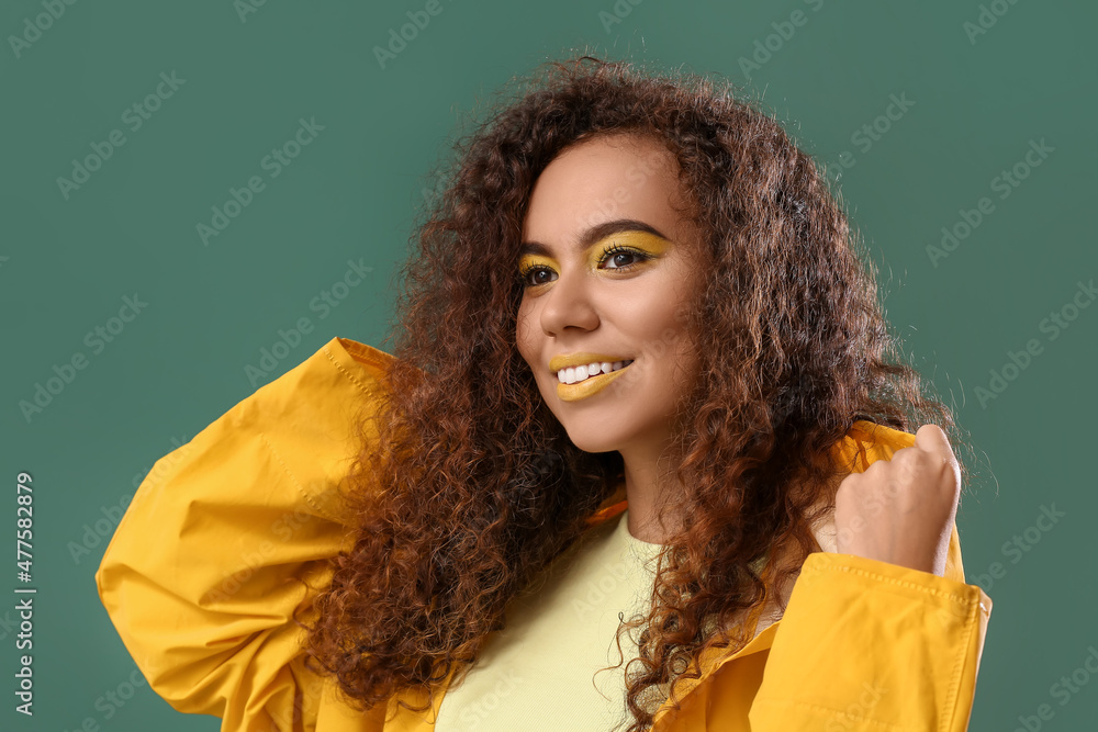 Beautiful African-American woman with makeup in yellow tones on color background Beautiful African-American woman with makeup in yellow tones on color background