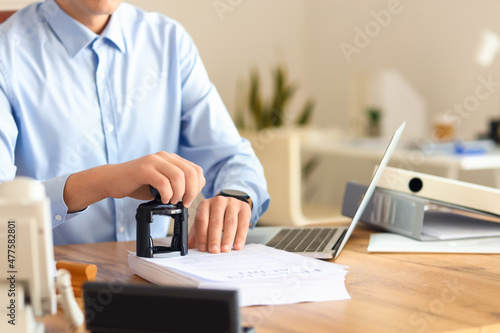 Young male notary public attaching seal to documents in office Fototapete