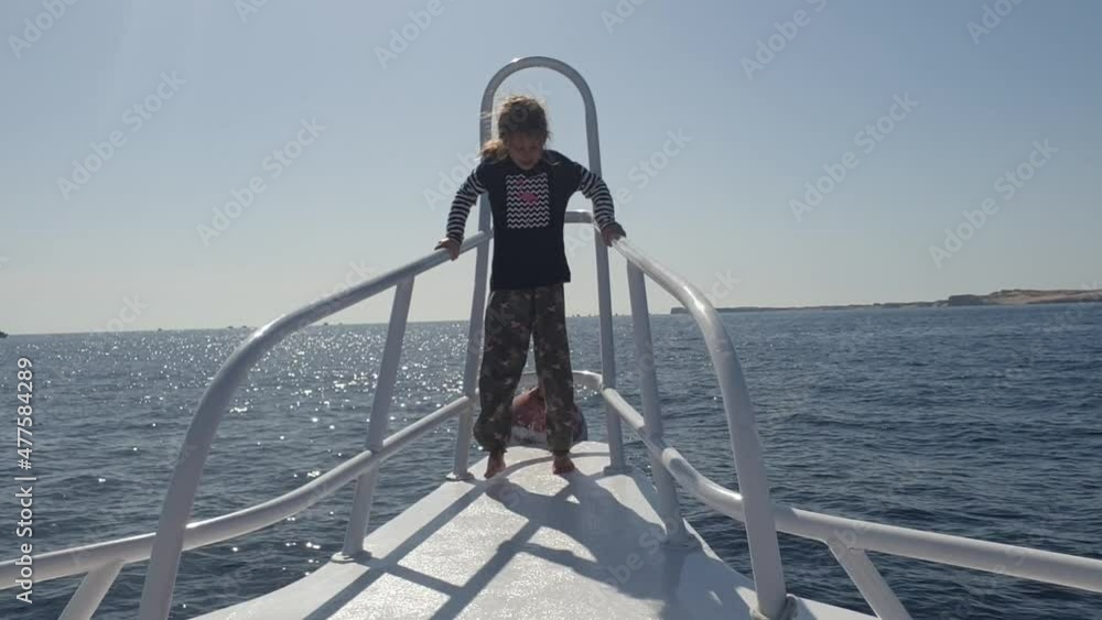 child girl on the bow of a yacht waves her hand in the open sea child girl on the bow of a yacht waves her hand in the open sea