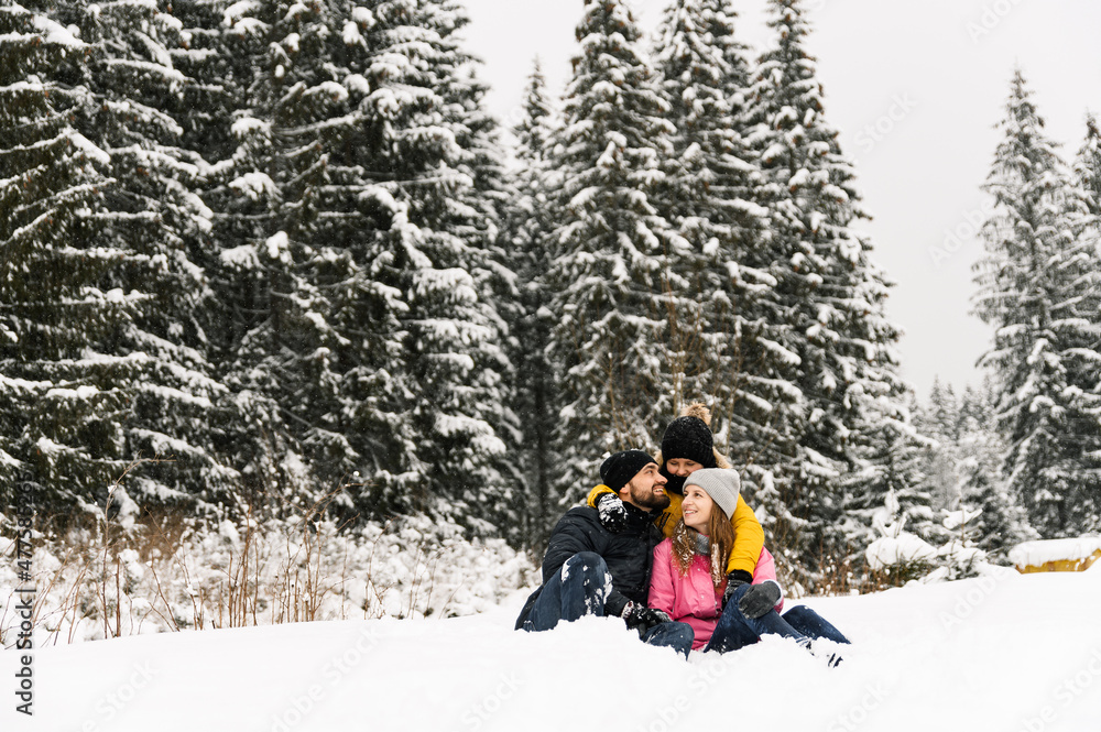 Happy family have fun in winter forest and looking at camera. Mother, father and son playing with snow. Family Christmas concept. Enjoying spending time together