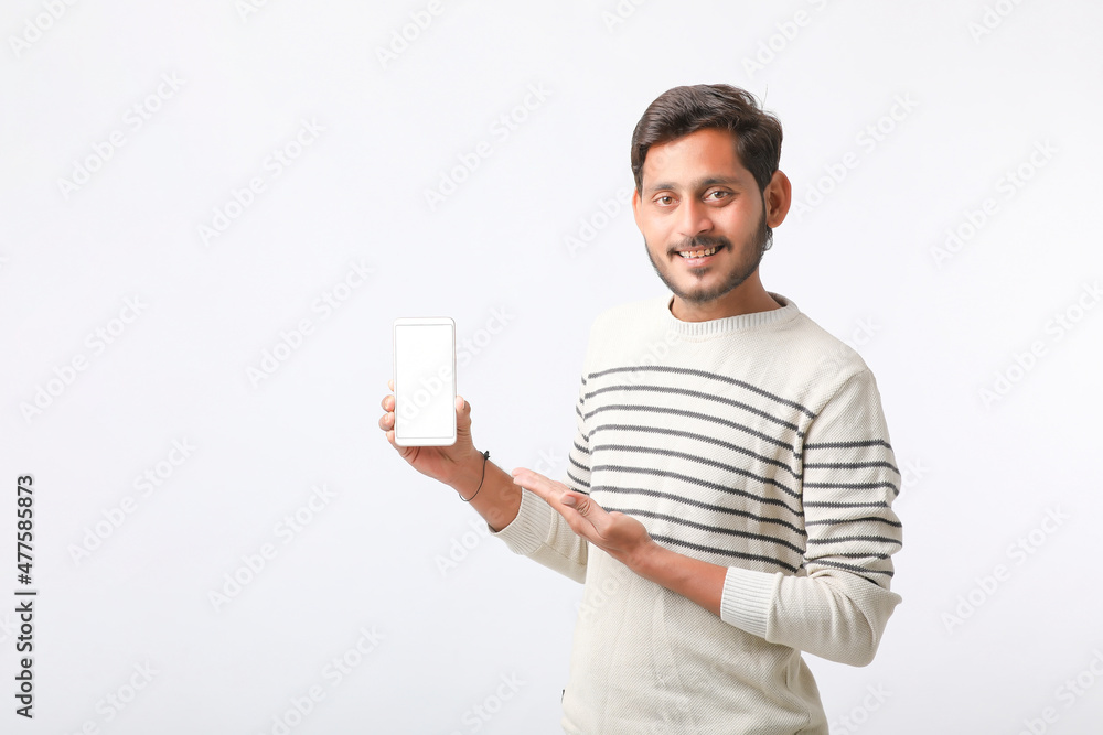Young indian man showing smartphone screen on white background. Young indian man showing smartphone screen on white background.