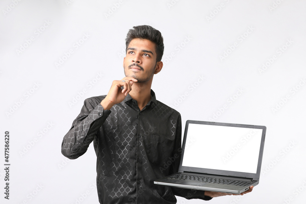 Young indian man showing laptop screen on white background. Young indian man showing laptop screen on white background.