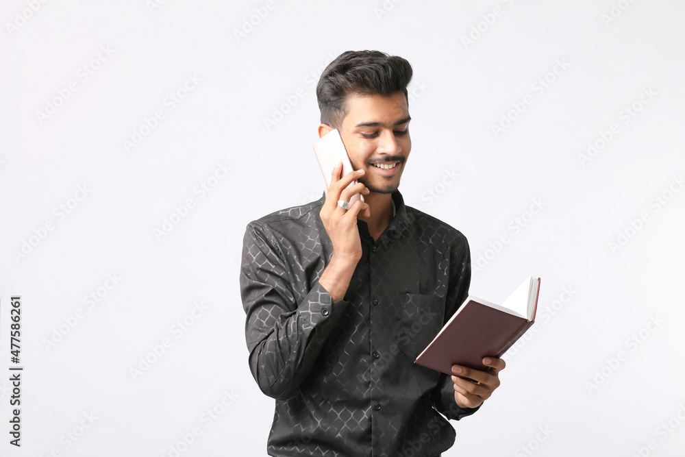 Young indian man talking on smartphone and giving expression on white background.