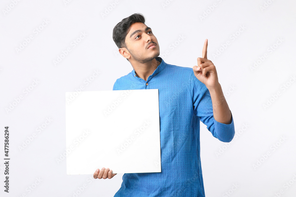 Indian man holding white board, promoting offers on festival season while wearing traditional cloths, standing over white background. Indian man holding white board, promoting offers on festival season while wearing traditional cloths, standing over white background.