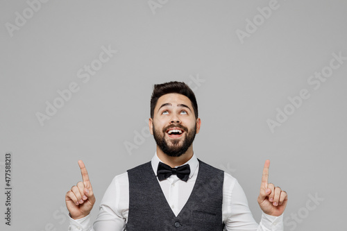 Young barista male waiter butler man wear white shirt vest elegant uniform work at cafe point index finger overhead on workspace isolated on plain grey background studio. Restaurant employee concept.