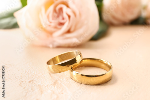 Golden wedding rings on beige background, closeup