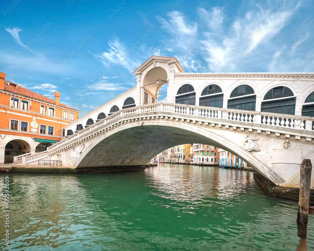 Naklejka premium Rialto bridge on The Grand Canal in Venice, Italy. Romantic architecture of Venice, famous landmark on a bright sunny day, blue sky with clouds.