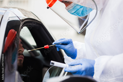 Female medical technician performing drive thru car swab sample collection on a young male