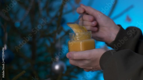 remove the thick honey from the jar with a spoon against the background of the Christmas tree in slow motion.