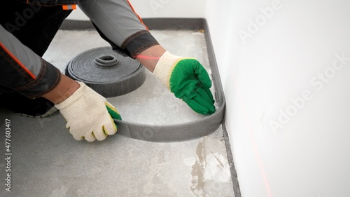 Bonding the floor with a damper tape. Installing a damping tape. Damping tape for floor screed. Before pouring the floor, tape the corners of the floor with tape.