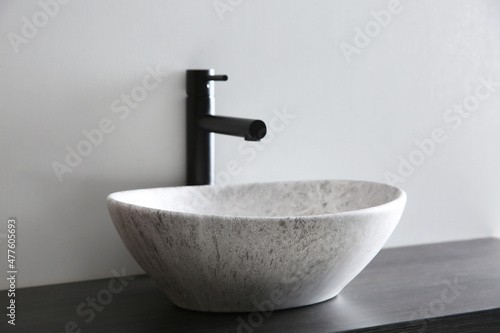 Stone vessel sink with faucet on wooden countertop