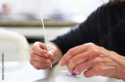 Detail of elderly woman hands with cotton swab of Covid-19 testing kit for self diagnose 