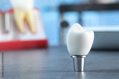 Photos Crown of dental implant with abutment on grey table in clinic, closeup