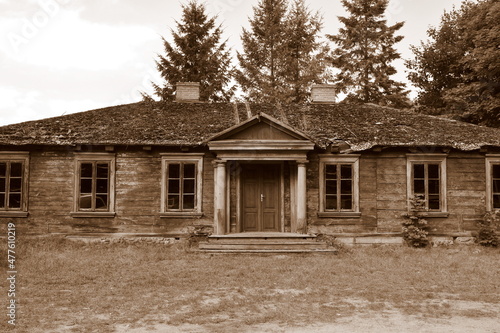 A close up on an old abandoned wooden house located in the middle of a forest or moor next to some trees, a well and a fence, spotted on a sunny summer day during a hike on a Polish countryside