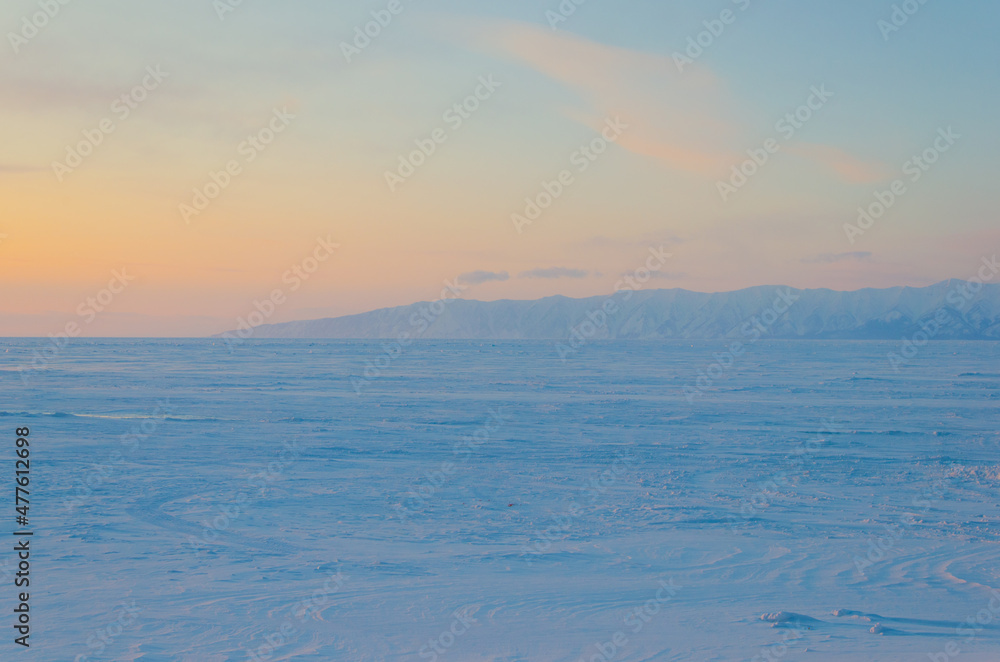 View of the freezing Lake Baikal in the snow at sunset.