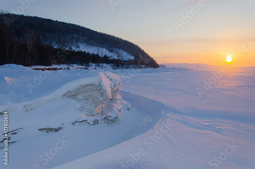 The shore of Lake Baikal is in the snow. A frozen lake at sunset.