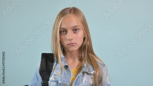 Teenage girl with backpack on blue background.