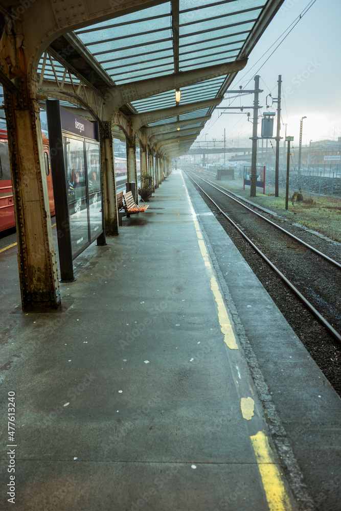 A vertical shot of an empty train station platform in Bergen, on a misty overcast gloomy day, Norway