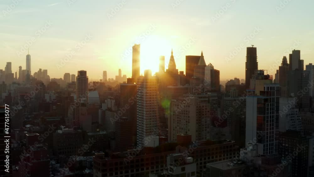 Fly above town. Silhouettes of tall office towers against setting sun. Manhattan, New York City, USA Fly above town. Silhouettes of tall office towers against setting sun. Manhattan, New York City, USA