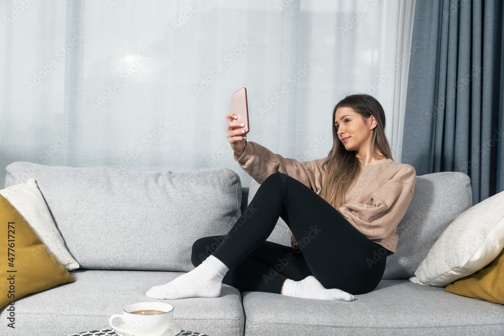 Young pretty and cute happy woman taking a selfie or self photographing her self with smartphone camera. Female making video call with friend showing her new hairstyle with new shampoo and regenerator Young pretty and cute happy woman taking a selfie or self photographing her self with smartphone camera. Female making video call with friend showing her new hairstyle with new shampoo and regenerator