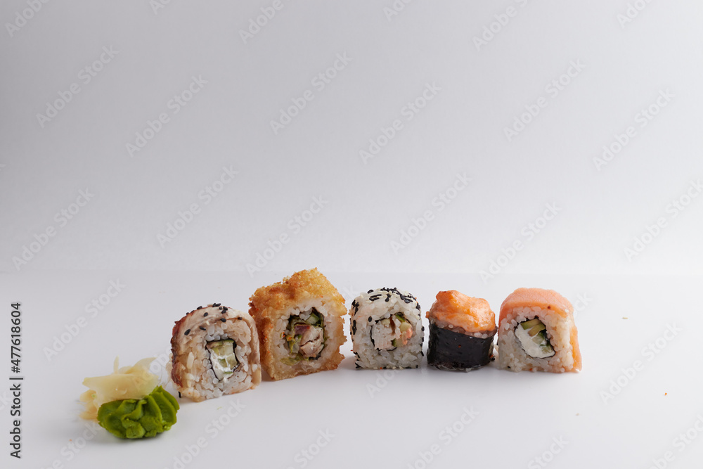 several different rolls on the table, Asian food, side view, light background, sushi, ginger and wasabi several different rolls on the table, Asian food, side view, light background, sushi, ginger and wasabi