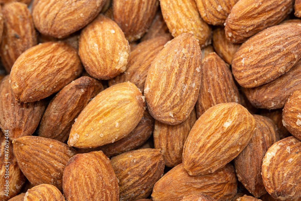 Close-up top view of almonds. Almonds in the middle in selective focus. Roasted salted almonds are ready to eat. They have salt crystals on them. Close-up top view of almonds. Almonds in the middle in selective focus. Roasted salted almonds are ready to eat. They have salt crystals on them.