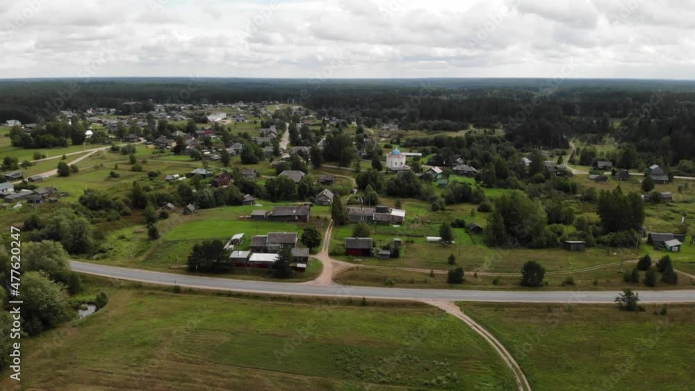 A village in Novgorod Oblast with a small old church with a blue roof. Wooden houses. Summer and forest. Aerial drone view. Flying over. Drone is moving forward. High quality 4k footage A village in Novgorod Oblast with a small old church with a blue roof. Wooden houses. Summer and forest. Aerial drone view. Flying over. Drone is moving forward. High quality 4k footage