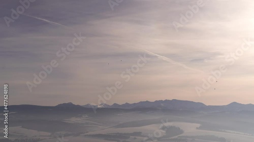 Wide open view of mountain range in winter with hot air balloons photo