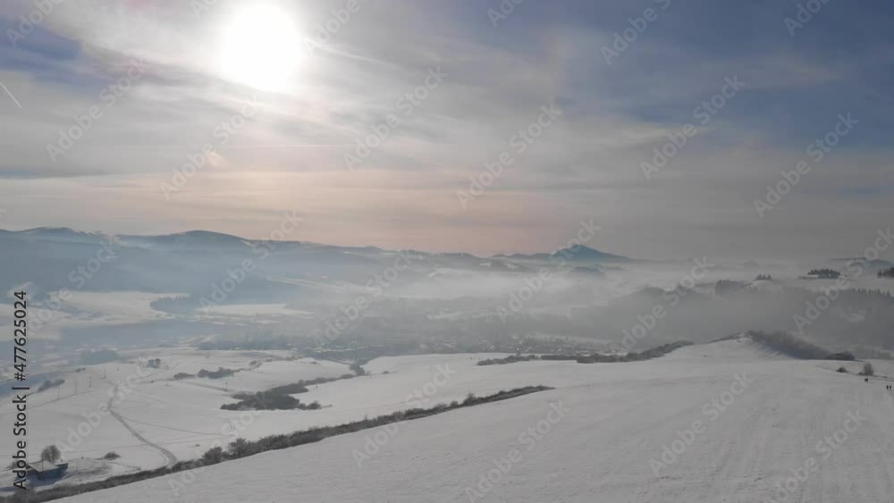 Slow aerial forward over wide open snow landscape with mountain range in distance Slow aerial forward over wide open snow landscape with mountain range in distance