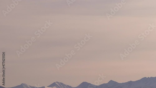 Slow tilt up over snowed in winter landscapes to hot air balloons photo